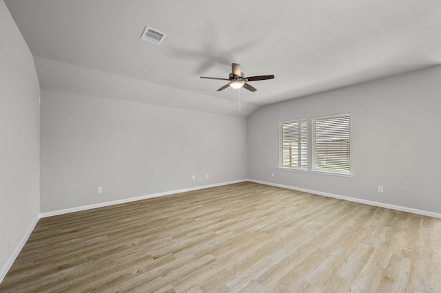 spare room with ceiling fan, vaulted ceiling, and light wood-type flooring