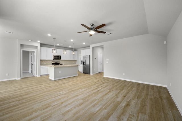 unfurnished living room with ceiling fan, vaulted ceiling, and light wood-type flooring