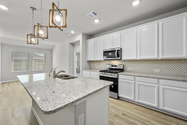 kitchen with stainless steel appliances, white cabinetry, sink, and decorative light fixtures