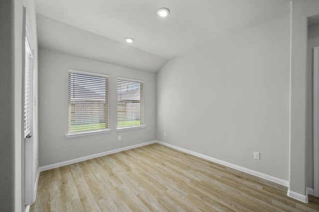 spare room with lofted ceiling and light hardwood / wood-style flooring