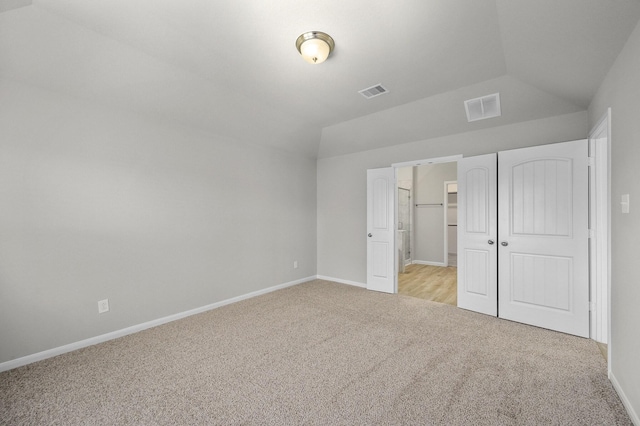 unfurnished bedroom with vaulted ceiling, light carpet, and a closet