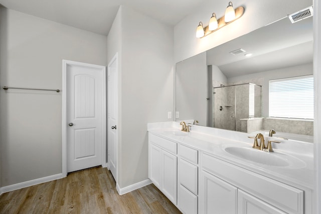 bathroom with dual bowl vanity, hardwood / wood-style flooring, and independent shower and bath