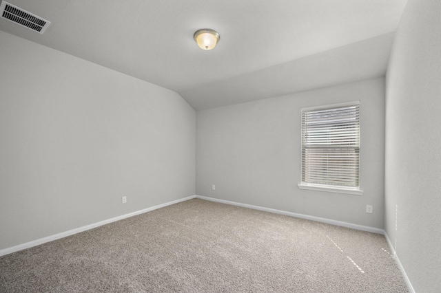 carpeted empty room featuring lofted ceiling