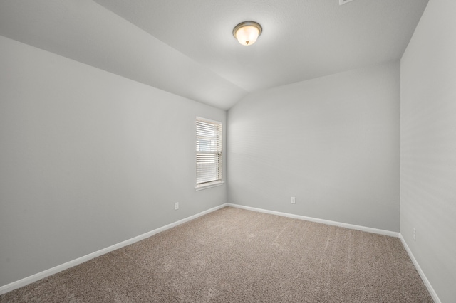 carpeted empty room featuring lofted ceiling