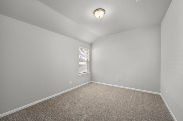 carpeted empty room featuring vaulted ceiling