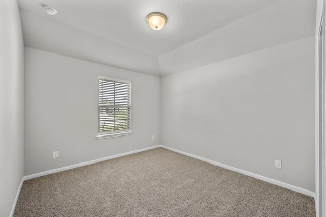 carpeted spare room with lofted ceiling