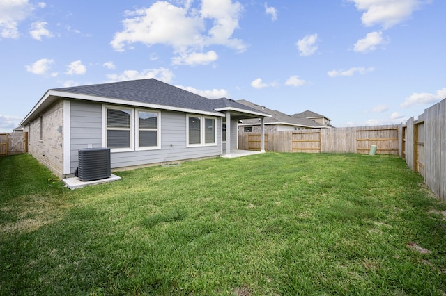 rear view of property featuring a lawn and central air condition unit