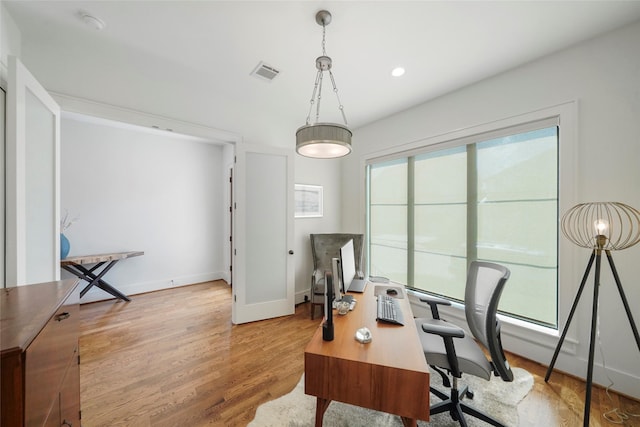 home office with light wood-type flooring and a wealth of natural light