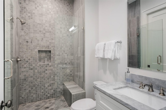 bathroom with vanity, toilet, and a shower with door