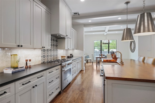 kitchen featuring white cabinetry, beamed ceiling, pendant lighting, light hardwood / wood-style floors, and stainless steel stove