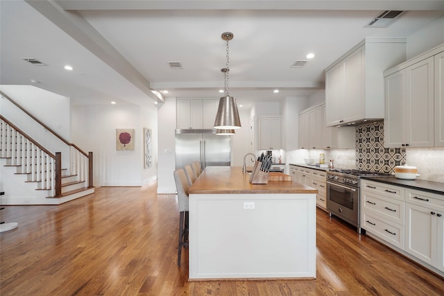 kitchen with light hardwood / wood-style flooring, high quality appliances, white cabinetry, hanging light fixtures, and an island with sink