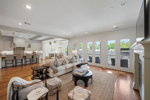 living room featuring a wealth of natural light, french doors, wood-type flooring, and a notable chandelier