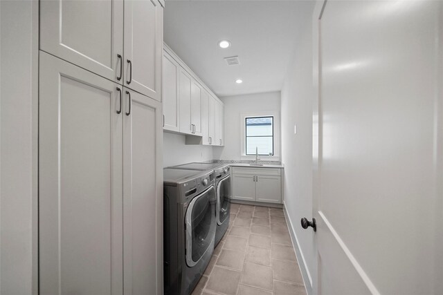 clothes washing area with washing machine and clothes dryer, sink, light tile patterned floors, and cabinets