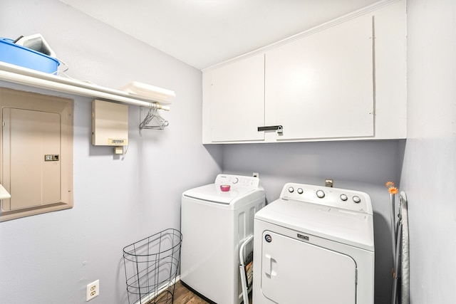 laundry area featuring hardwood / wood-style floors, electric panel, washing machine and dryer, and cabinets