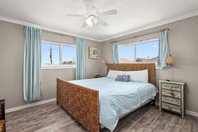 bedroom with baseboards, multiple windows, wood finished floors, and crown molding