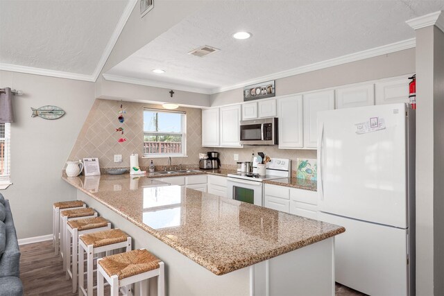 kitchen featuring white appliances, white cabinetry, and visible vents