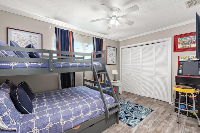 bedroom featuring a textured ceiling, ornamental molding, wood finished floors, and visible vents