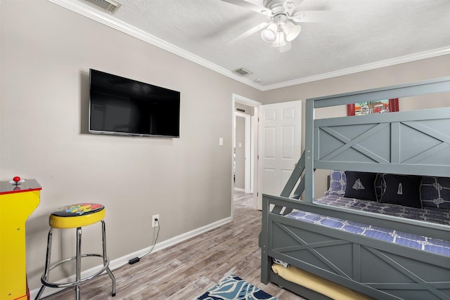 bedroom featuring visible vents, ornamental molding, and wood finished floors