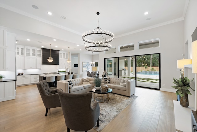 living room with light wood-type flooring, crown molding, and a notable chandelier