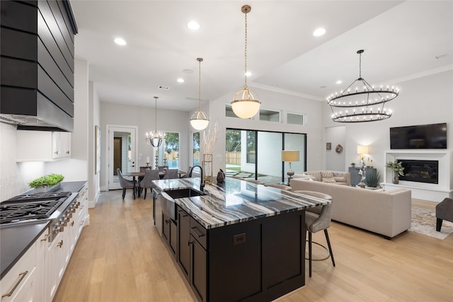 kitchen featuring hanging light fixtures, dark stone counters, sink, and light hardwood / wood-style flooring