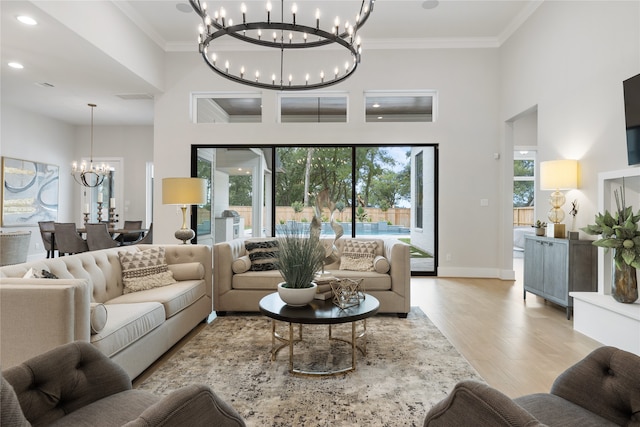 living room with ornamental molding, light wood-type flooring, a chandelier, and plenty of natural light