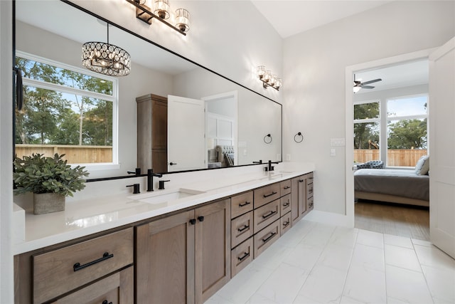 bathroom with ceiling fan with notable chandelier, a wealth of natural light, and vanity