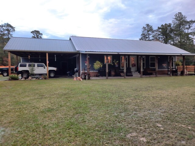 back of property with a porch, a carport, and a yard