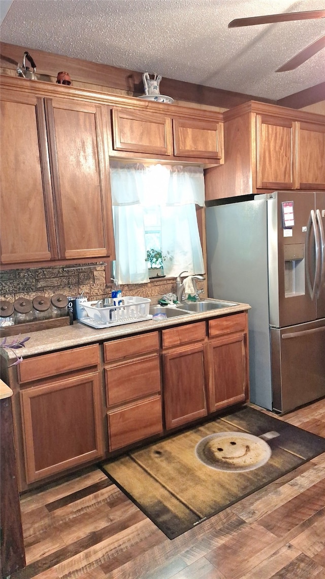 kitchen featuring a textured ceiling, ceiling fan, stainless steel fridge with ice dispenser, light hardwood / wood-style floors, and sink