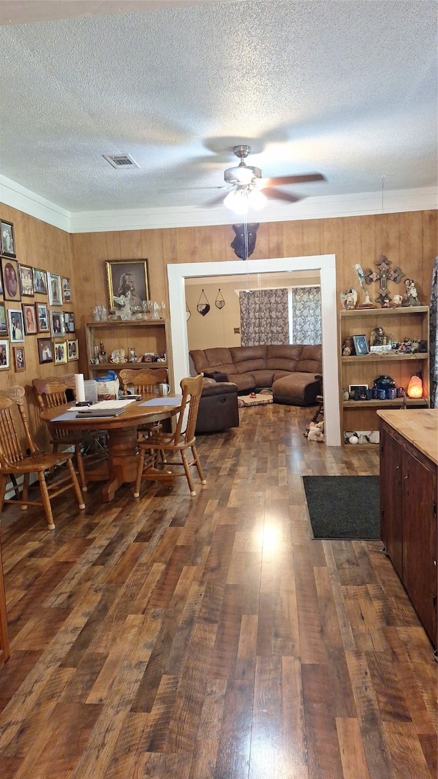 dining space with ceiling fan, dark wood-type flooring, ornamental molding, and a textured ceiling