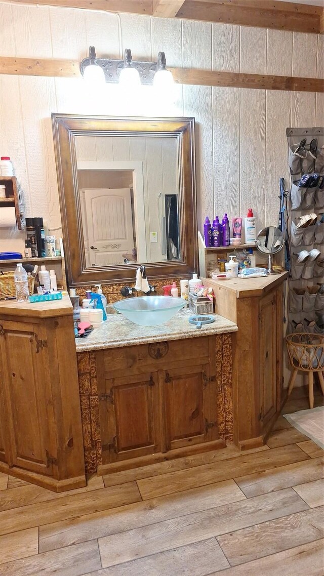 bathroom featuring wood walls, hardwood / wood-style flooring, and vanity