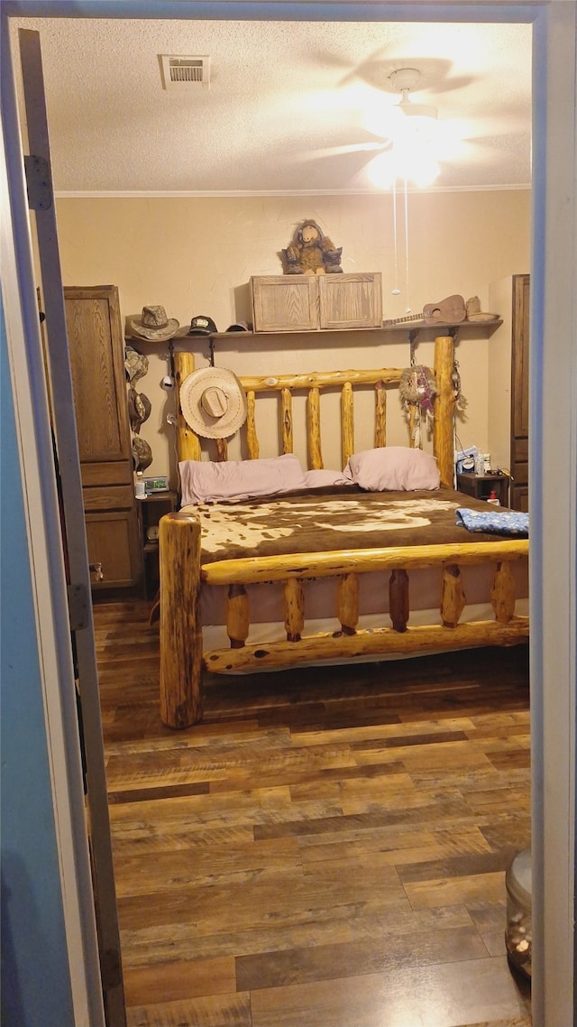 bedroom with a textured ceiling, dark wood-type flooring, and ceiling fan