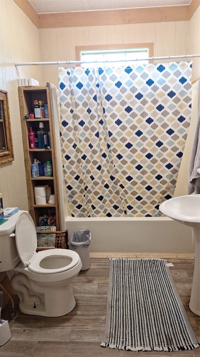 bathroom featuring shower / bath combo with shower curtain, wood-type flooring, and toilet