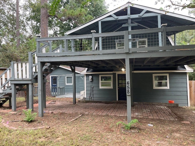 back of property with a wooden deck and a patio