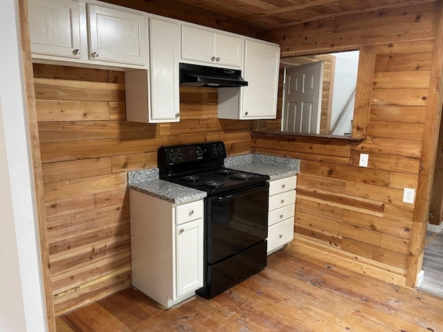 kitchen featuring black electric range, light hardwood / wood-style flooring, wooden walls, and white cabinets