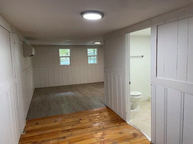 basement with light hardwood / wood-style flooring and a wall unit AC