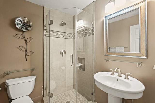 bathroom featuring toilet, sink, and a shower with shower door