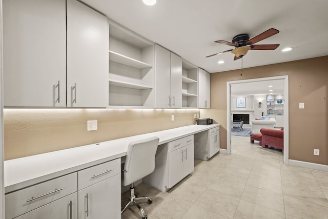 interior space with built in desk, light tile patterned floors, and ceiling fan