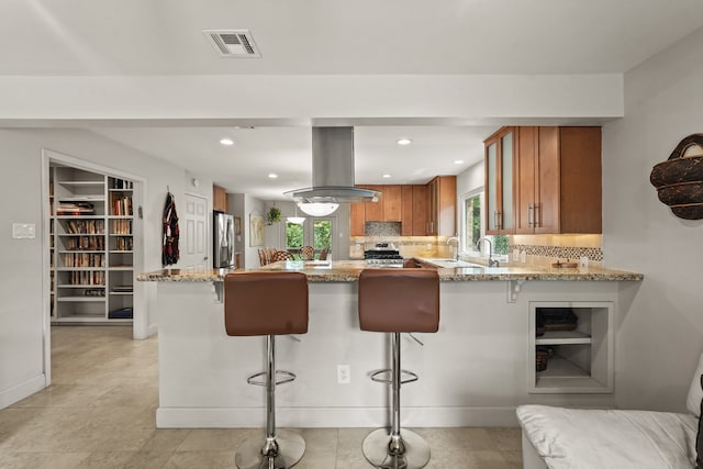 kitchen featuring island exhaust hood, kitchen peninsula, stainless steel appliances, and a breakfast bar