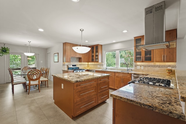 kitchen featuring island exhaust hood, light stone counters, a healthy amount of sunlight, and appliances with stainless steel finishes