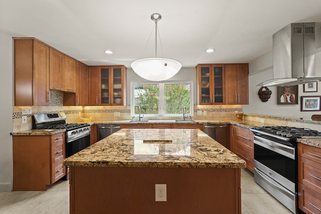 kitchen with appliances with stainless steel finishes, a kitchen island, light stone countertops, and island range hood