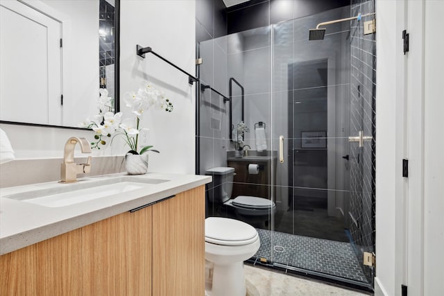 bathroom featuring toilet, vanity, and a shower with door