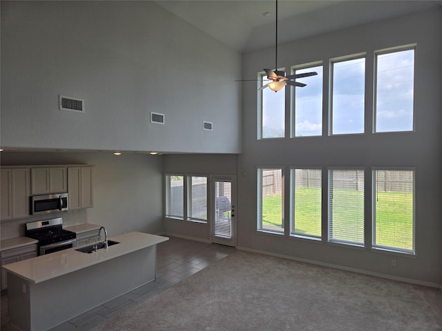 kitchen featuring carpet floors, sink, a center island, ceiling fan, and stainless steel appliances