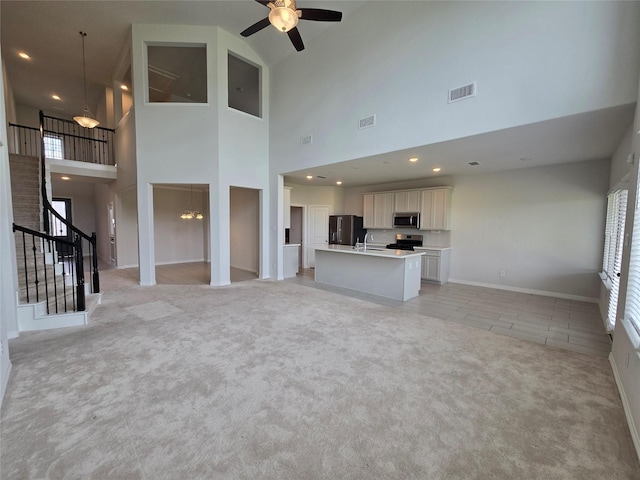 unfurnished living room with ceiling fan and light colored carpet