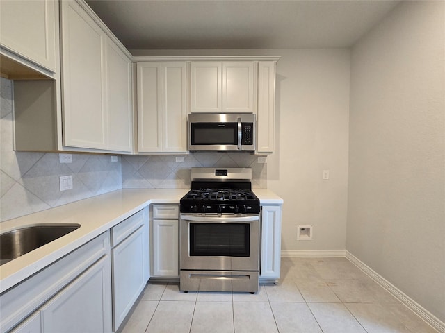 kitchen with stainless steel appliances, white cabinetry, light tile patterned flooring, and backsplash