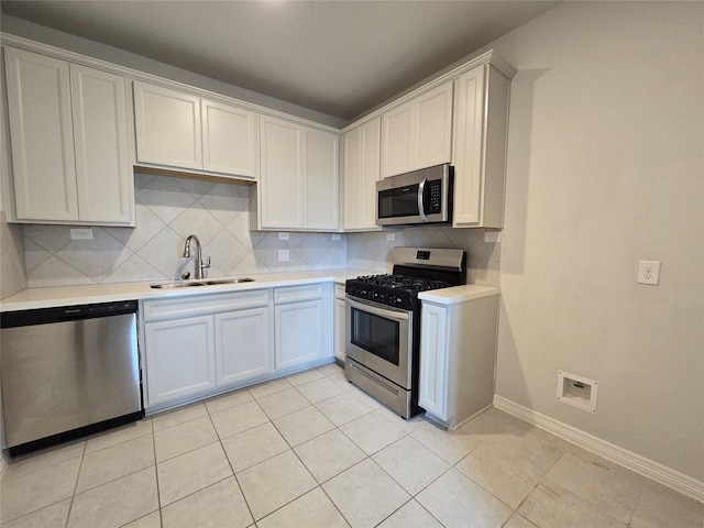 kitchen featuring sink, white cabinetry, light tile patterned floors, appliances with stainless steel finishes, and decorative backsplash