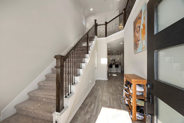 stairs with hardwood / wood-style floors and a towering ceiling