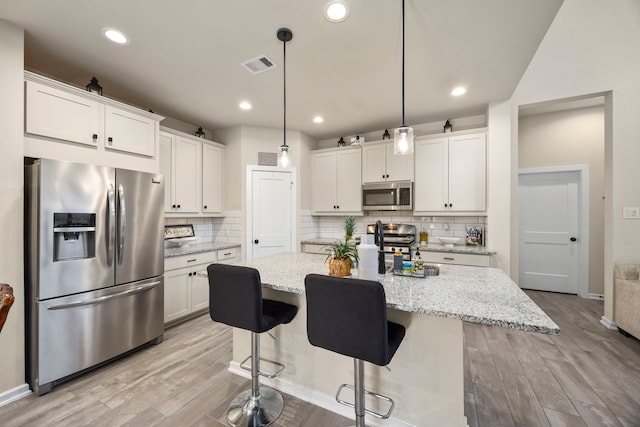 kitchen with backsplash, stainless steel appliances, white cabinetry, and light wood-type flooring