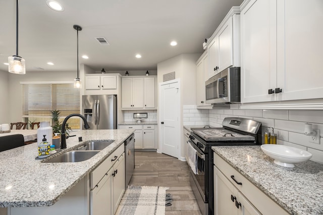 kitchen featuring pendant lighting, tasteful backsplash, light stone counters, sink, and stainless steel appliances