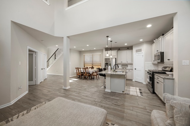 kitchen with an island with sink, sink, decorative light fixtures, a breakfast bar area, and stainless steel appliances