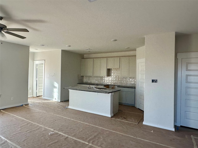 kitchen featuring backsplash, sink, ceiling fan, a textured ceiling, and a kitchen island